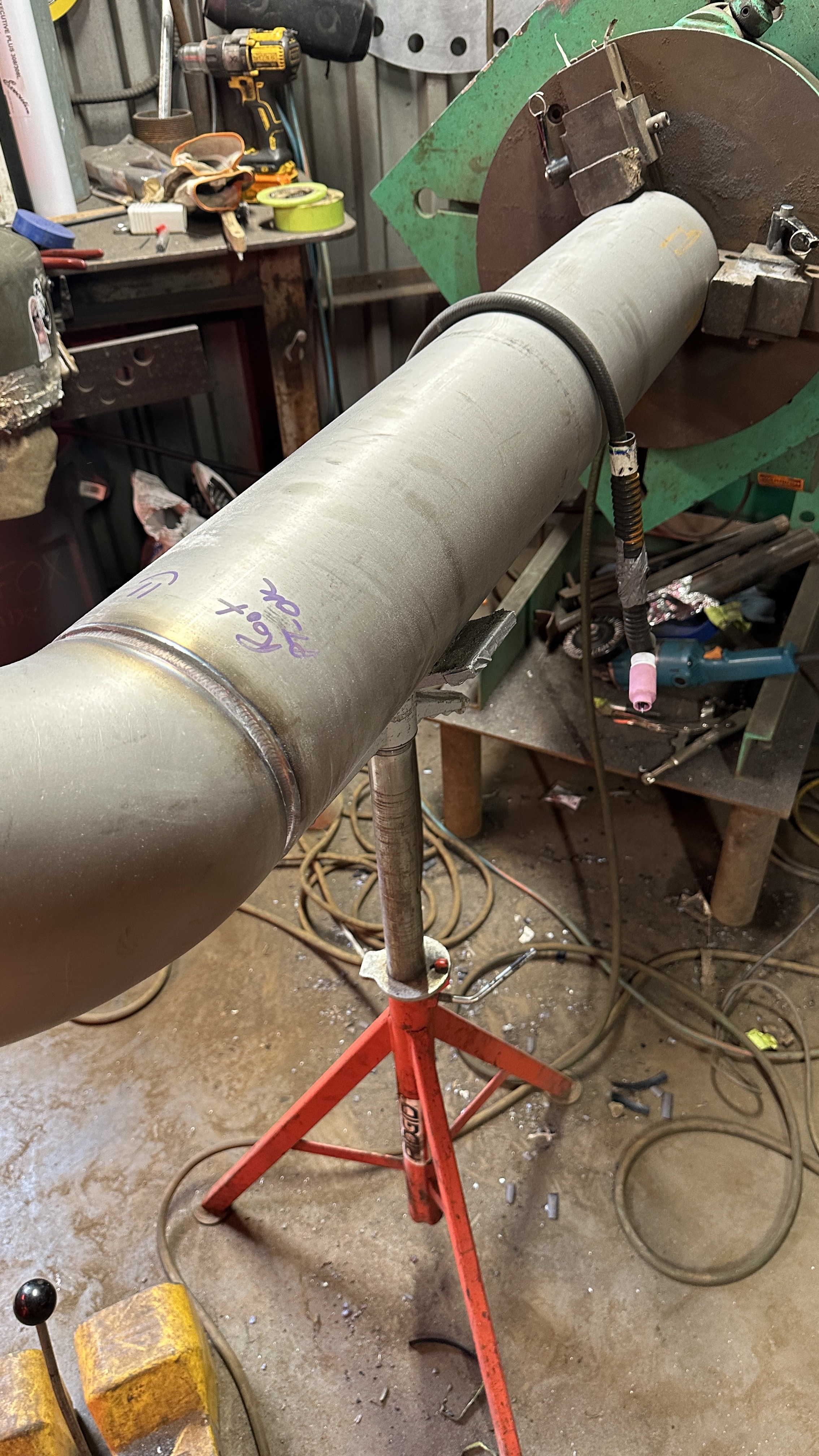 Stainless steel pipe assembly staged in a fabrication shop with welding equipment